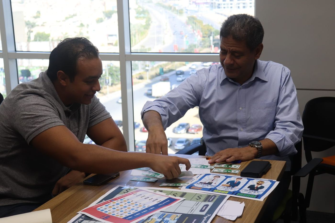 Two participants placing employee cards and game money on the Psychology of Money board